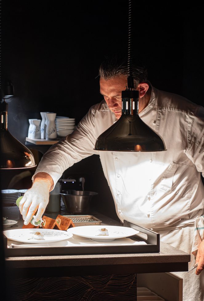 Le Chef Julien Pilati en pleine concentration, préparant un plat délicat avec des pommes vertes.