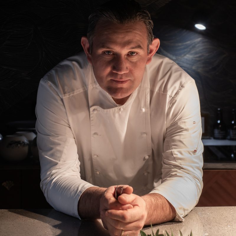 Le Chef Julien Pilati en pleine concentration, préparant un plat délicat avec des pommes vertes.